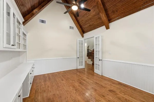 a view of empty room with wooden floor and fan
