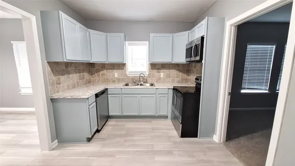 a kitchen with white cabinets and sink