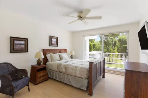 a bedroom with a bed a couch and a flat tv screen next to a window
