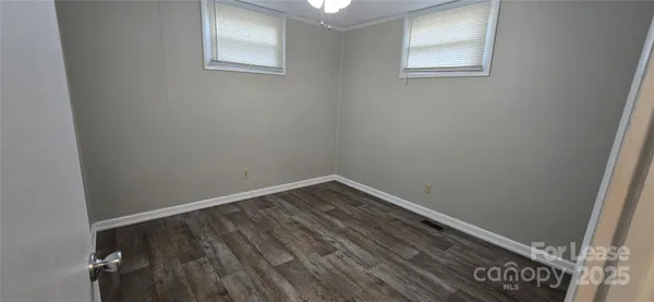 a view of an empty room with wooden floor and closet