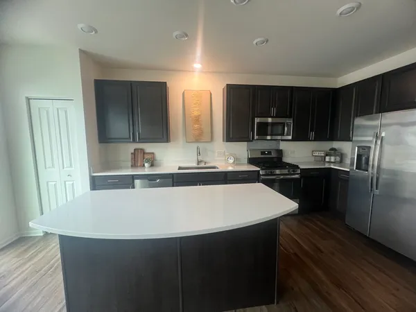 a kitchen with kitchen island a sink a stove a refrigerator and cabinets