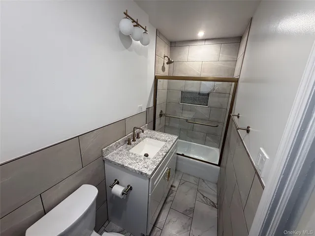 a bathroom with a granite countertop sink a toilet and shower