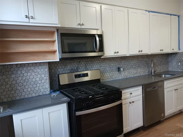 a kitchen with granite countertop white cabinets and appliances