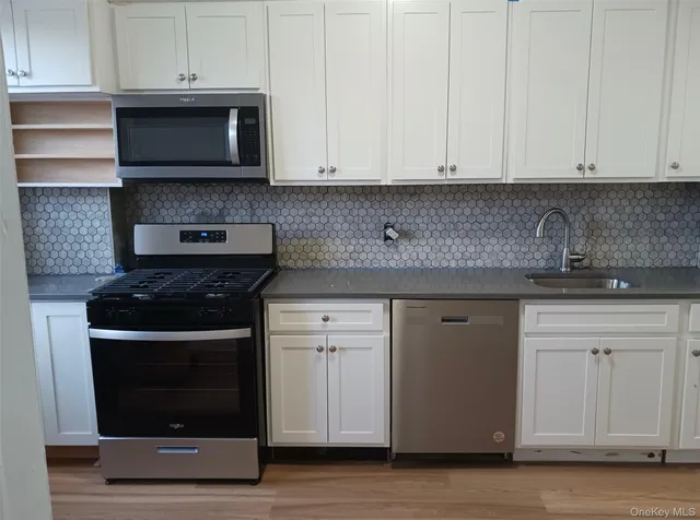 a kitchen with stainless steel appliances granite countertop white cabinets and a stove a oven with white countertops