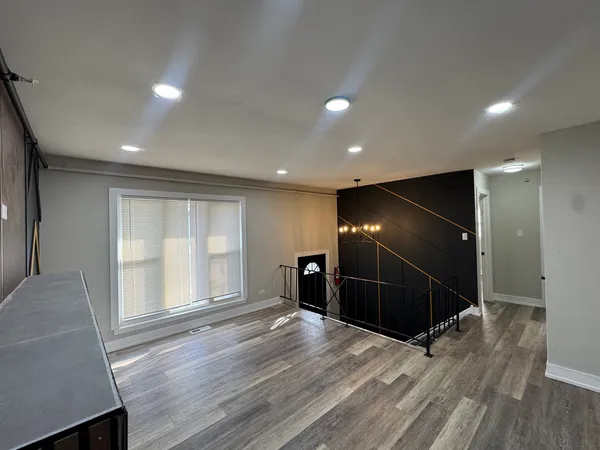 a view of an empty room with wooden floor and windows