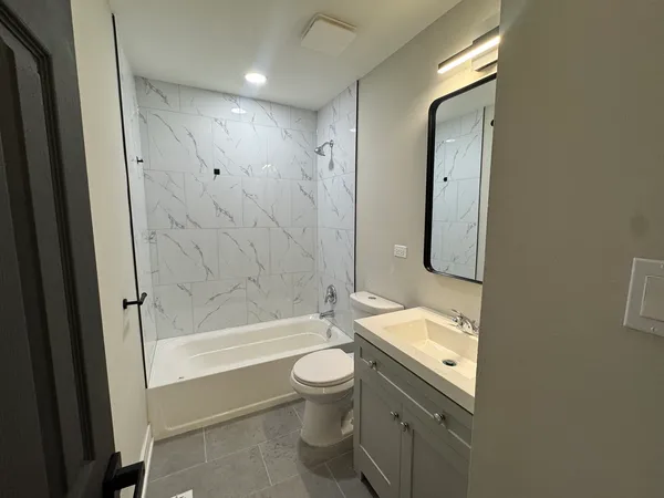 a bathroom with a granite countertop toilet a sink and bathtub