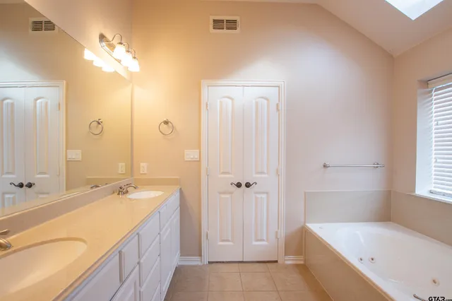 a spacious bathroom with a tub sink and mirror