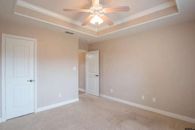 an empty room with a chandelier fan and closet area