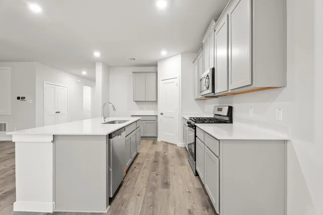 a kitchen with stainless steel appliances granite countertop a lot of counter space and wooden floors