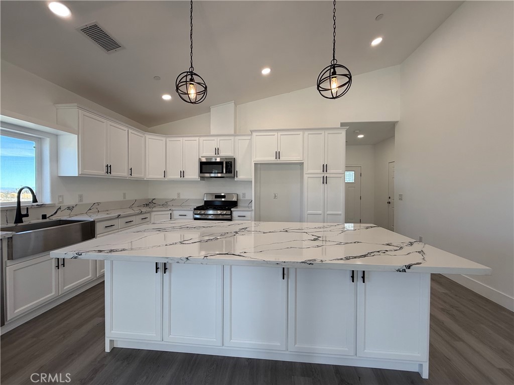 2115 Seville Place Pinon Hills, CA 92372 - Photo 19 of 31 a kitchen with a stove a sink a refrigerator and white cabinets with wooden floor