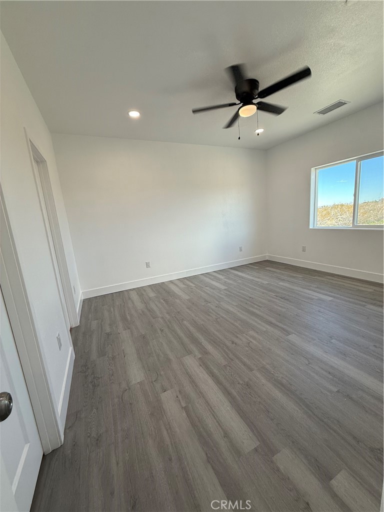 2115 Seville Place Pinon Hills, CA 92372 - Photo 26 of 31 an empty room with wooden floor and windows