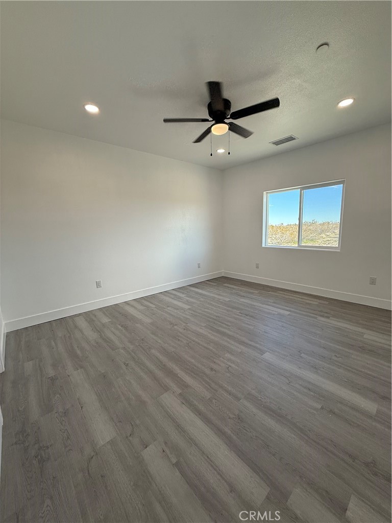 2115 Seville Place Pinon Hills, CA 92372 - Photo 27 of 31 an empty room with wooden floor ceiling fan and windows