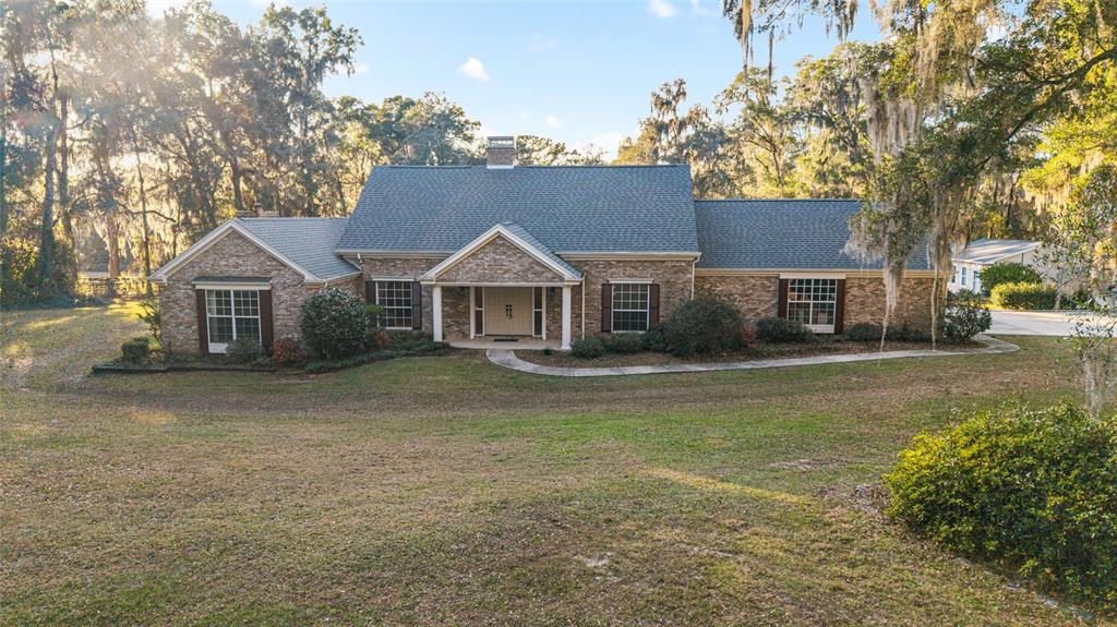 a front view of a house with a garden and tree