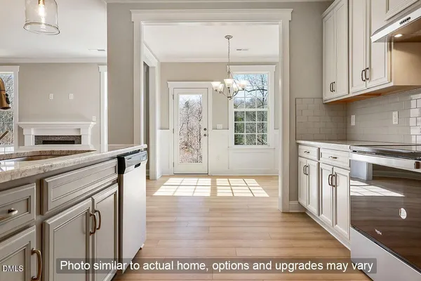 a open kitchen with stainless steel appliances granite countertop a stove top oven a sink dishwasher and white cabinets with wooden floor