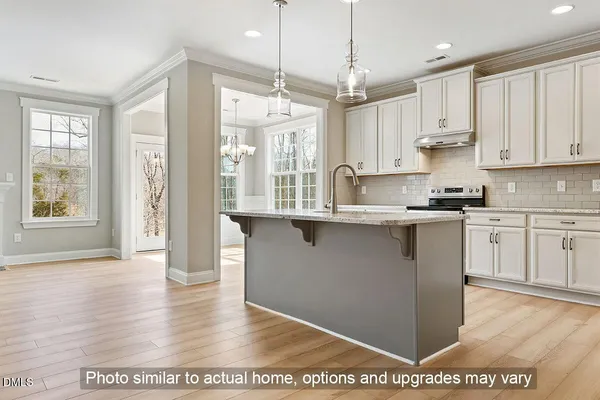 a kitchen with stainless steel appliances granite countertop a stove a sink and white cabinets with wooden floor