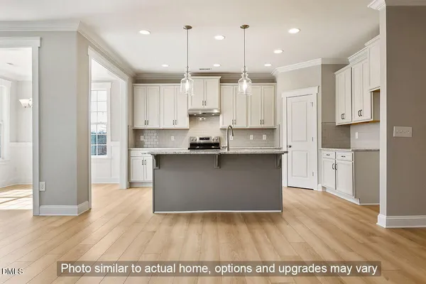 a kitchen with kitchen island granite countertop a stove a refrigerator a sink and white cabinets with wooden floor