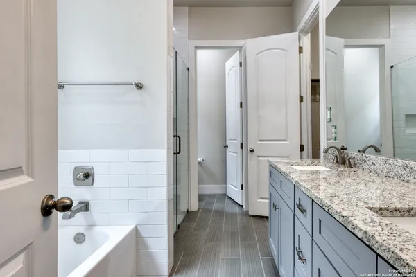 a bathroom with a granite countertop sink a mirror and a bathtub