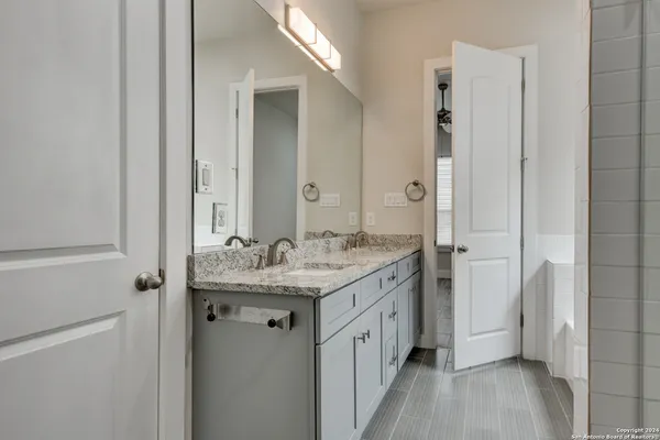 a bathroom with a granite countertop sink a mirror and a shower