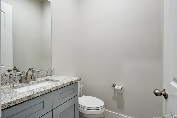 a bathroom with a granite countertop sink a toilet and mirror