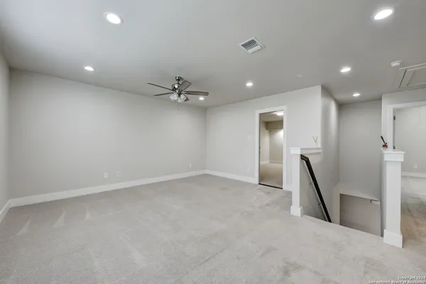 an empty room with a ceiling fan and hallway