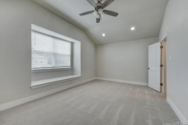 an empty room with windows and fan