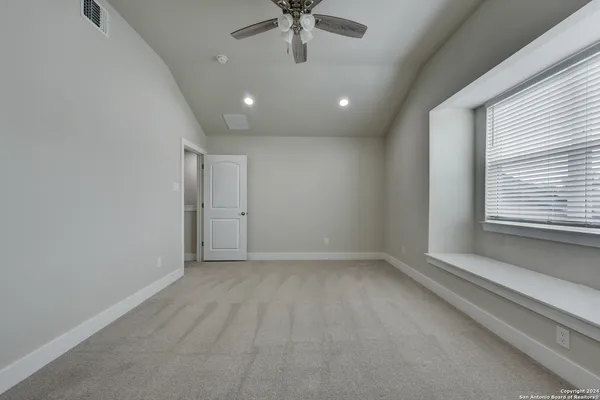 en empty room with windows and ceiling fan