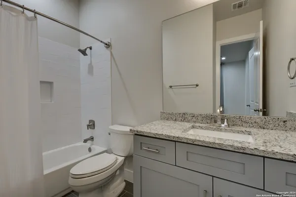 a bathroom with a granite countertop sink toilet and shower