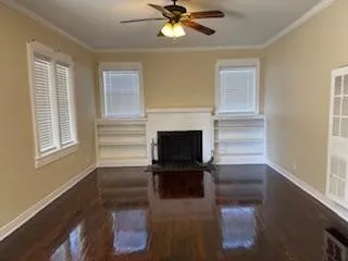 a view of a livingroom with a fireplace a ceiling fan and windows