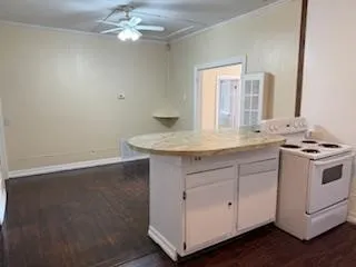a view with granite countertop a sink a stove chandelier and wooden floor