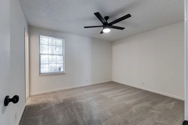 an empty room with a window and a fan