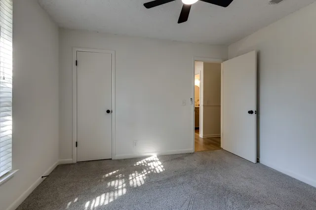 a view of an empty room with chandelier fan