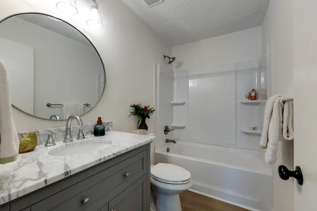 a bathroom with a granite countertop sink a toilet and a mirror