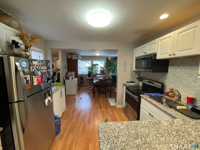 a kitchen with stainless steel appliances granite countertop a refrigerator stove top oven and a sink