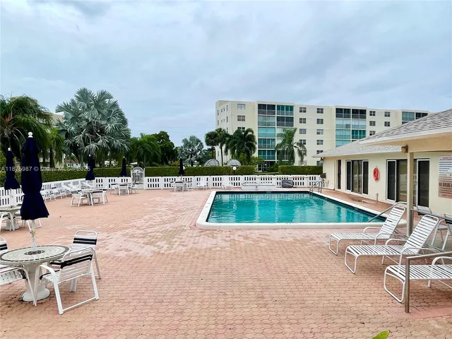 a view of swimming pool with lawn chairs and plants