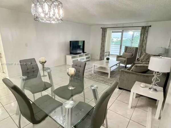 a living room with furniture a chandelier and a flat screen tv