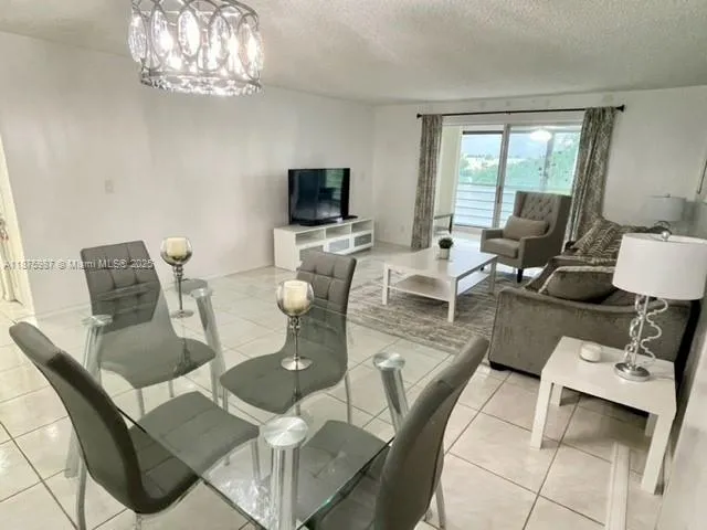 a living room with furniture a chandelier and a flat screen tv