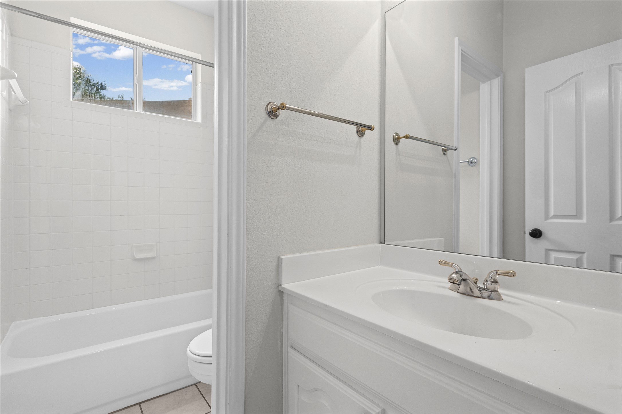 10700 Pointe View Drive Austin, TX 78738 - Photo 15 of 35 A well-lit bathroom with a bright window above the tub, featuring a clean white vanity and coordinating tile.