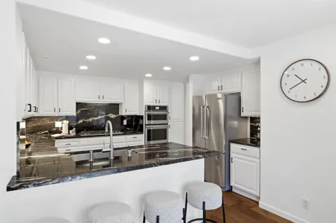 a kitchen with stainless steel appliances granite countertop a sink refrigerator and cabinets