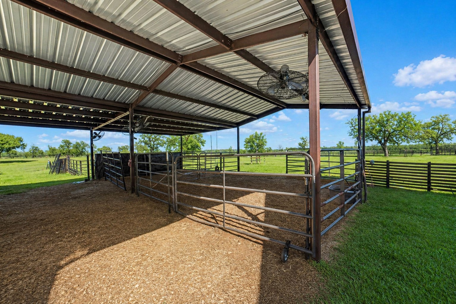 3103 Brundrett Road Wallis, TX 77485 - Photo 41 of 50 Covered livestock shelter with sturdy pipe fencing and wide-open pasture views, ideal for ranch living.