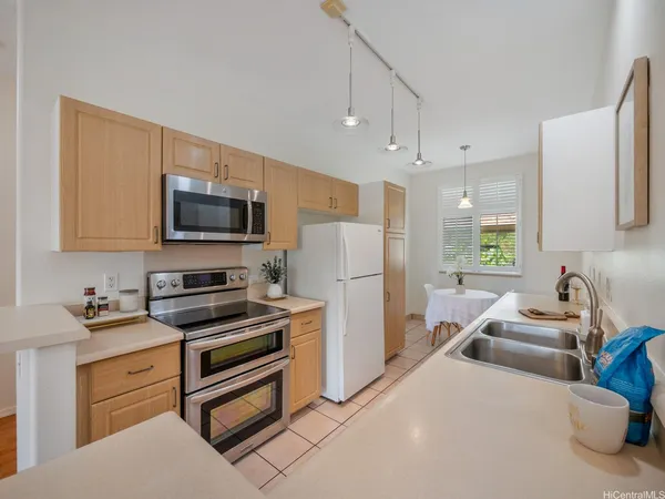 a kitchen with stainless steel appliances a stove a sink a refrigerator a microwave a sink and cabinets