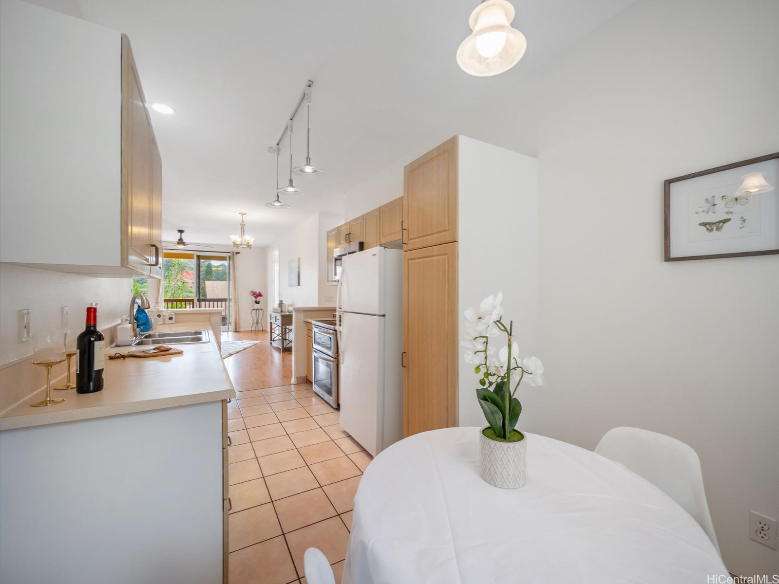 95-982 Wikao Street, Unit L203 Mililani, HI 96789 - Photo 8 of 25 a kitchen with stainless steel appliances kitchen island granite countertop a refrigerator a stove a sink dishwasher and white cabinets with wooden floor