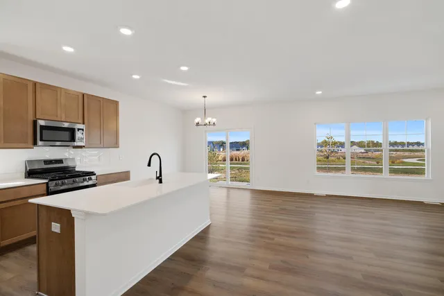 a large kitchen with stainless steel appliances a large counter top a stove a chimney a sink and a refrigerator