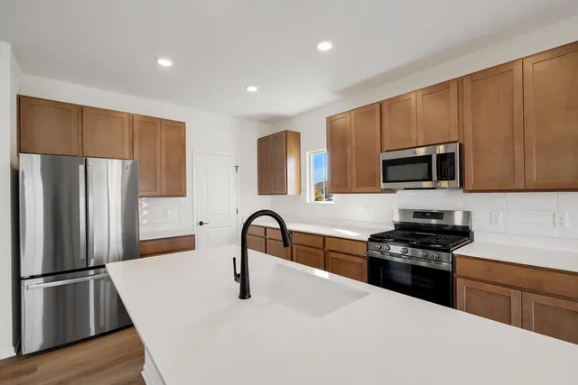 a kitchen with granite countertop a refrigerator stove and microwave