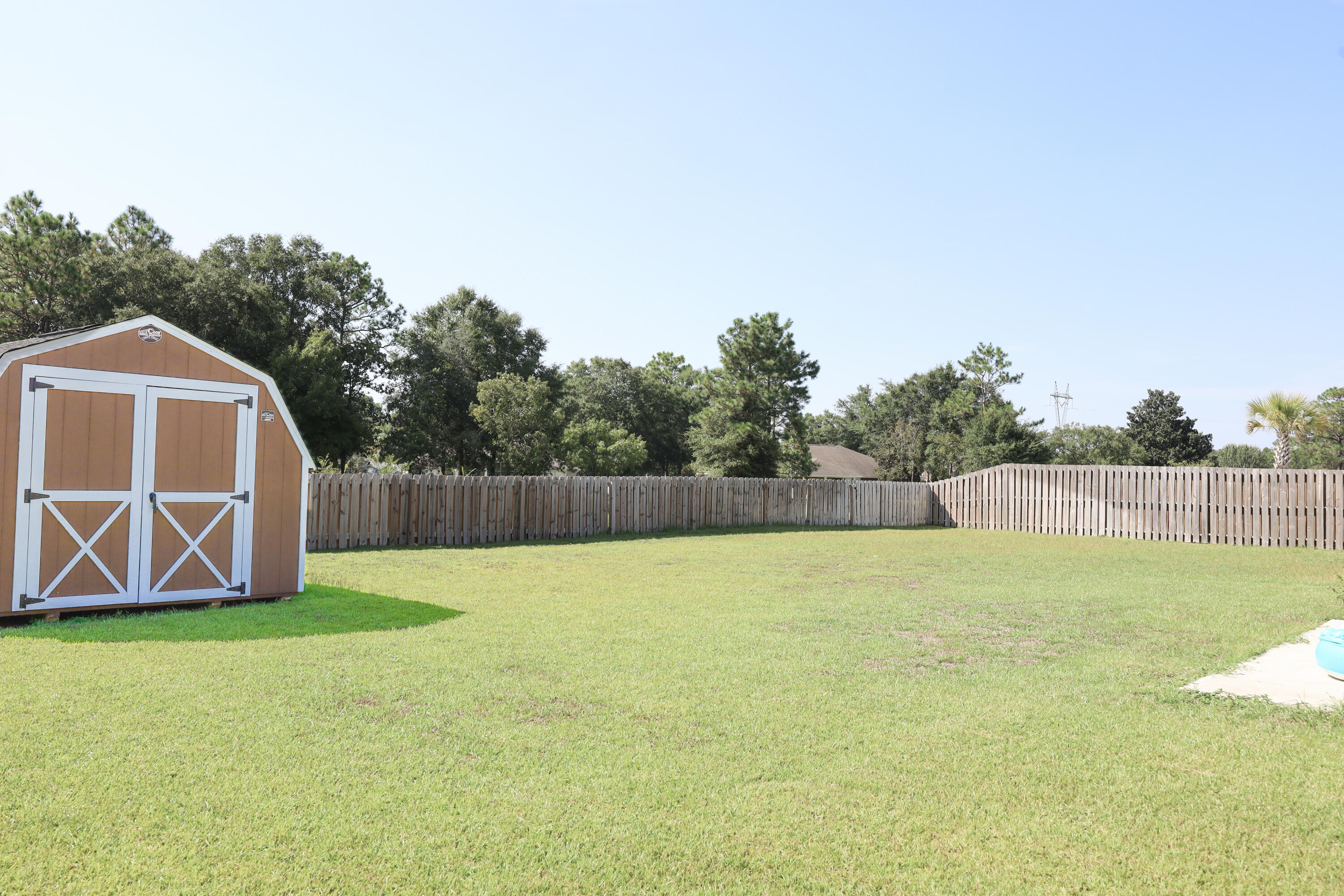 2896 Chancery Lane Crestview, FL 32539 - Photo 29 of 33 a view of a backyard with a barbeque and wooden fence