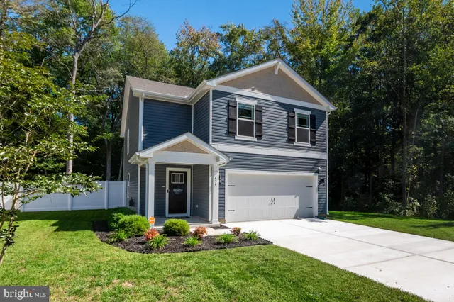 a front view of a house with a yard and trees