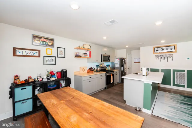 a large kitchen that has a lot of cabinets a sink and a wooden floor in it