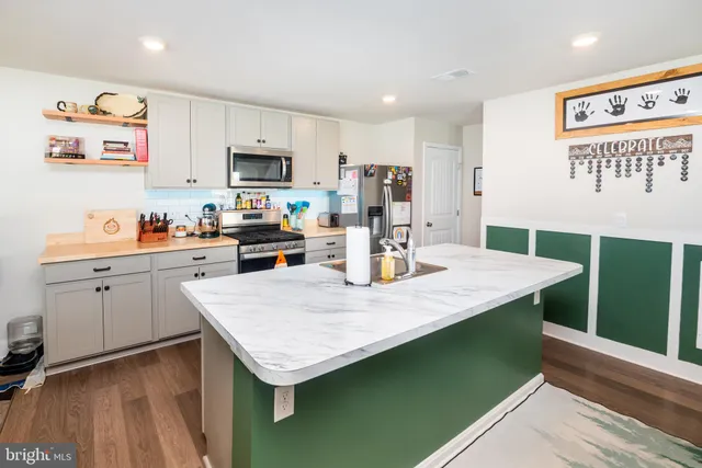 a kitchen with stainless steel appliances granite countertop a kitchen island a stove a sink dishwasher and a refrigerator with wooden floor