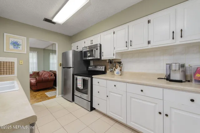 a kitchen with white cabinets and black appliances