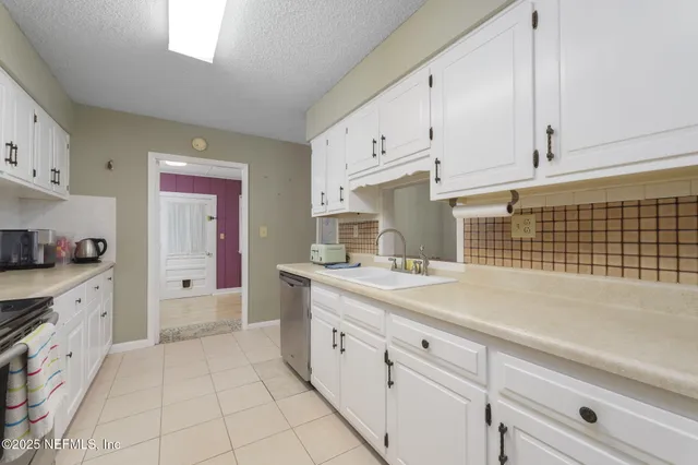 a kitchen with white cabinets and sink