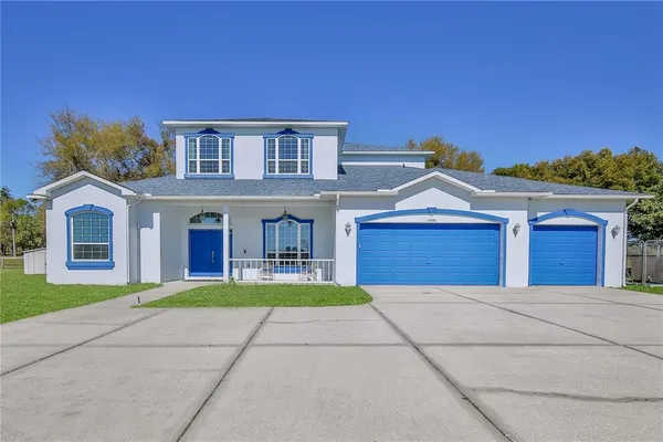 a view of house with a big yard and large trees